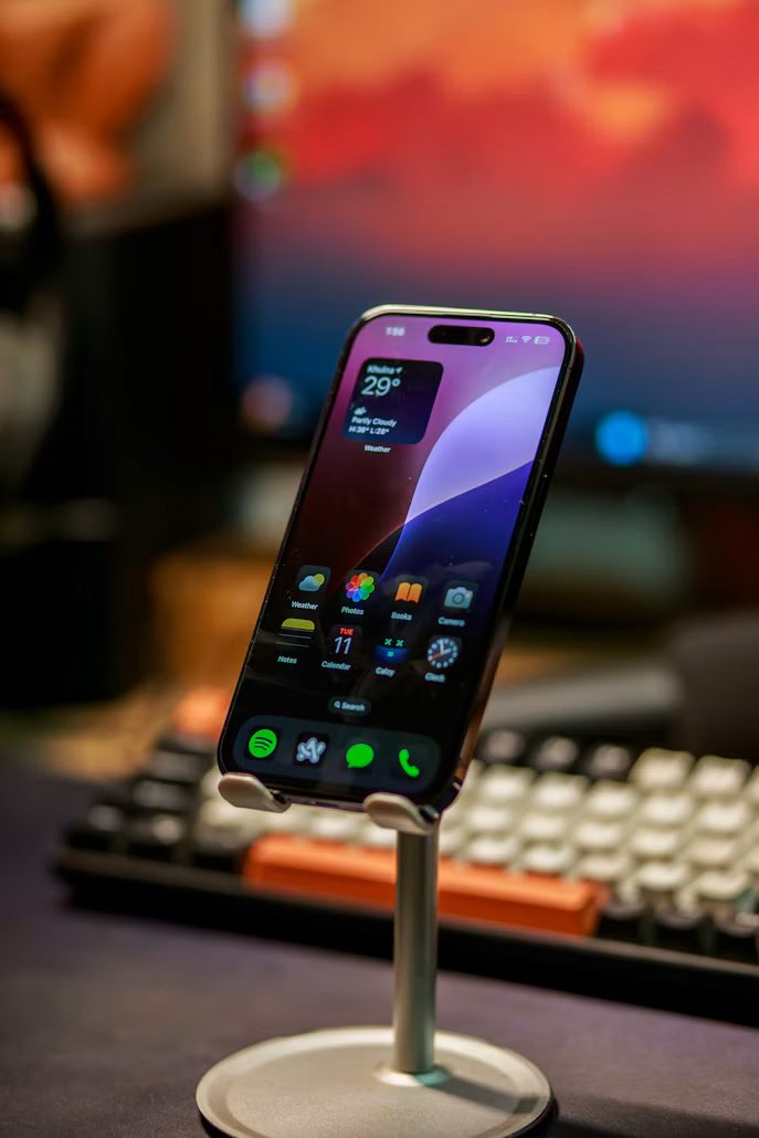 Un iPhone récent posé sur un support, l’écran d’accueil allumé